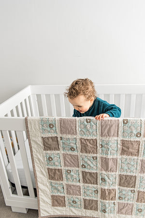 baby-boy-playing-in-crib-with-brown-blue-neutral-tone-minimalist-baby-blanket