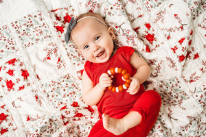 new-baby-girl-in-red-jumper-playing-with-wood-toy-on-christmas-blanket-by-sugar-owl-design