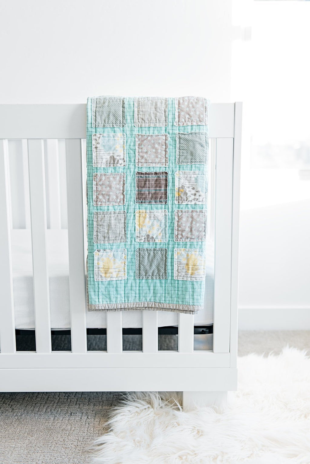 gender-neutral-baby-room-with-handmade-quilt-hanging-over-white-crib